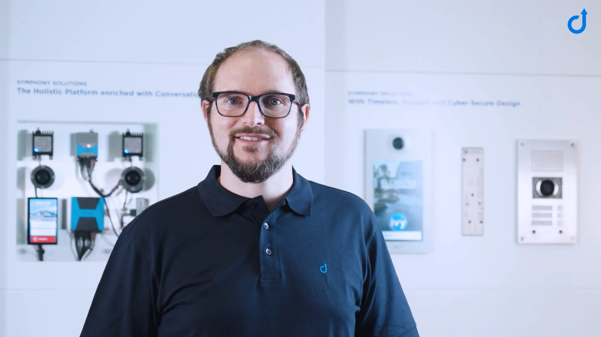Mann vor Sprechanlagen & Komm.-Systemen Lächelnder Mann vor einer Präsentation moderner Sprechanlagen und Kommunikationssysteme.